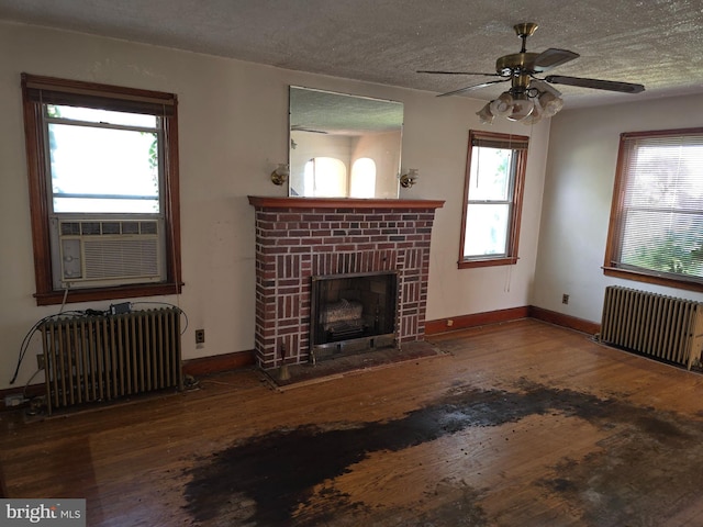 unfurnished living room featuring a fireplace, hardwood / wood-style floors, radiator heating unit, and a textured ceiling