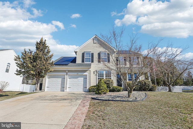 traditional-style home featuring a front yard, fence, driveway, and roof mounted solar panels