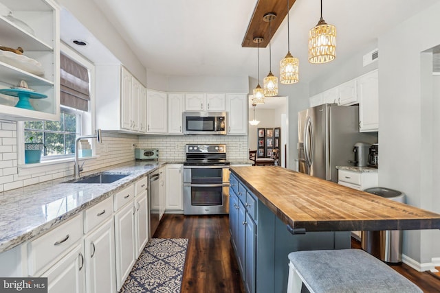 kitchen with white cabinetry, wooden counters, stainless steel appliances, and a sink