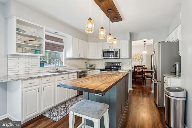 kitchen with a sink, stainless steel appliances, white cabinets, and wood counters