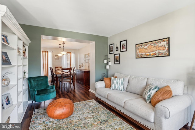 living area featuring an inviting chandelier, baseboards, and wood finished floors