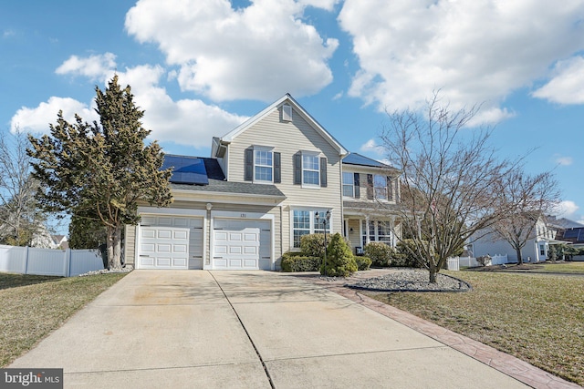 traditional-style home featuring roof mounted solar panels, concrete driveway, a front yard, and fence