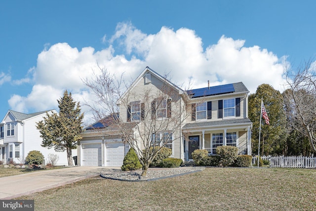 traditional-style house with roof mounted solar panels, a front yard, driveway, and fence