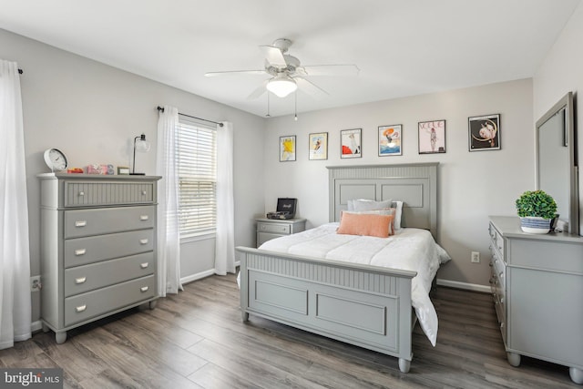 bedroom featuring baseboards, wood finished floors, and a ceiling fan