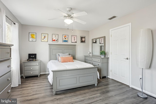 bedroom featuring ceiling fan, visible vents, baseboards, and wood finished floors