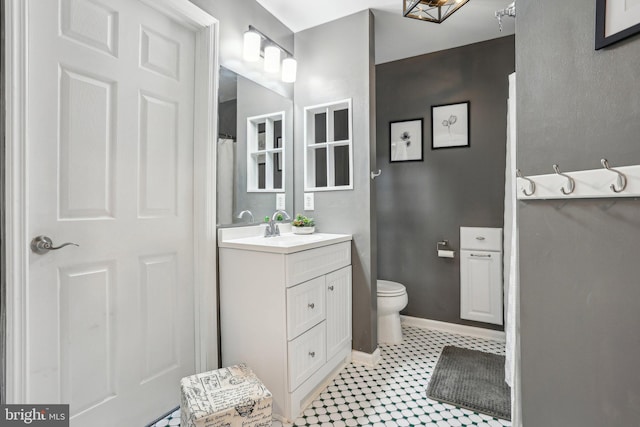 bathroom featuring vanity, toilet, and baseboards