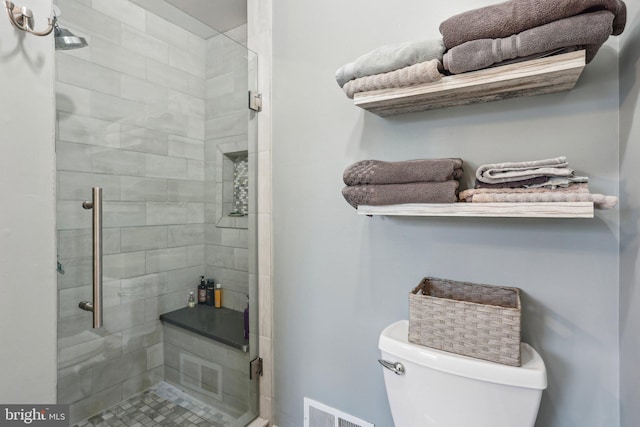 bathroom with visible vents, toilet, and a shower stall