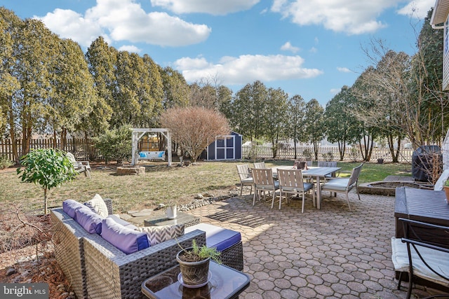 view of patio featuring an outdoor living space with a fire pit, a shed, a fenced backyard, an outbuilding, and outdoor dining space