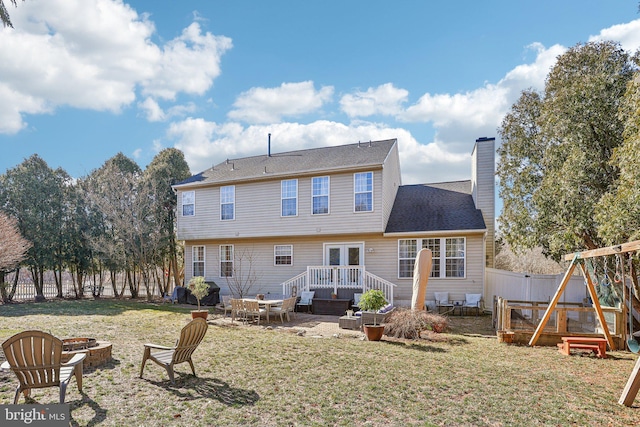 rear view of house featuring a wooden deck, an outdoor fire pit, a chimney, a yard, and a fenced backyard