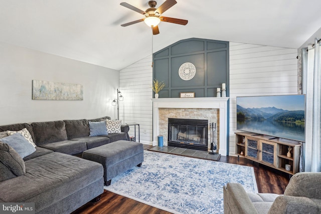 living room with dark wood-style flooring, a ceiling fan, a fireplace with flush hearth, and vaulted ceiling