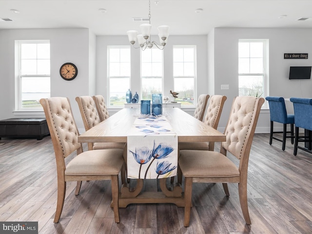 dining space with a healthy amount of sunlight, visible vents, and wood finished floors