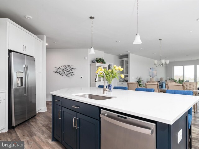 kitchen with stainless steel appliances, white cabinets, a sink, an island with sink, and wood finished floors