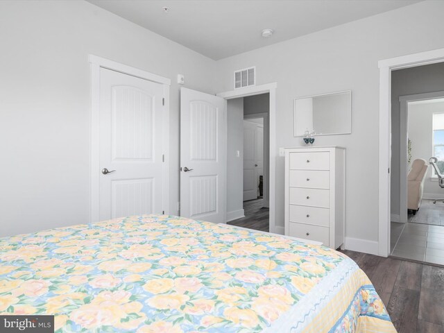 bedroom featuring baseboards, visible vents, and wood finished floors