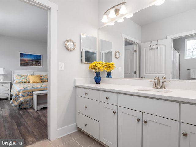 ensuite bathroom with tile patterned flooring, baseboards, vanity, and ensuite bath