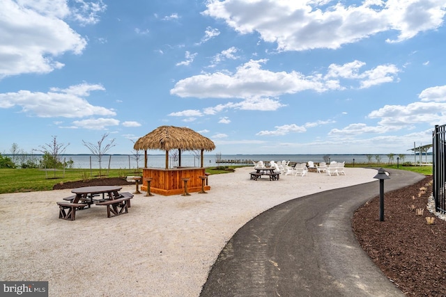 view of community with a jacuzzi, a fire pit, a water view, fence, and a gazebo