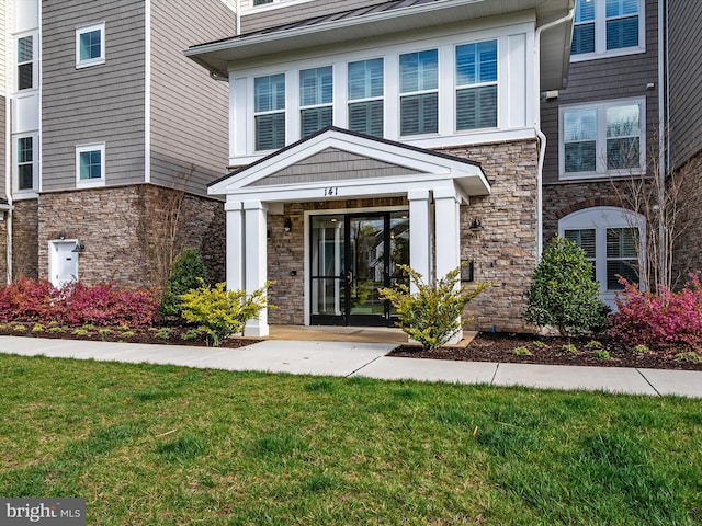 property entrance featuring stone siding and a yard