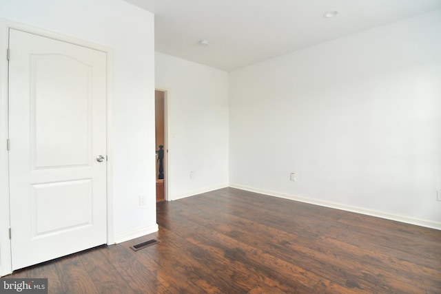 unfurnished room featuring dark wood finished floors, baseboards, and visible vents