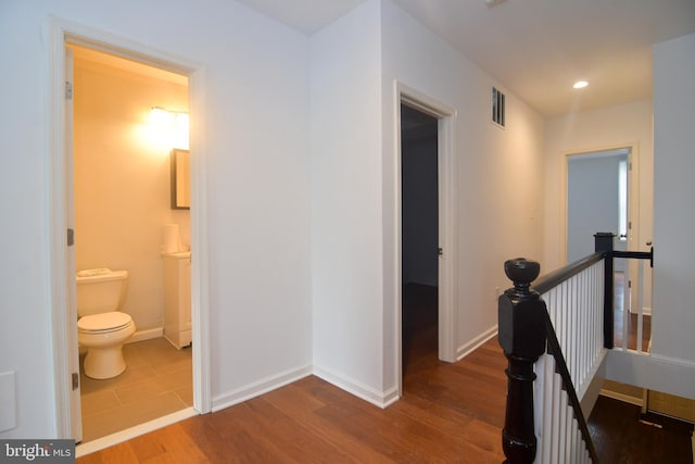 corridor featuring visible vents, baseboards, an upstairs landing, recessed lighting, and wood finished floors