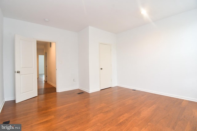 spare room with visible vents, baseboards, and wood finished floors