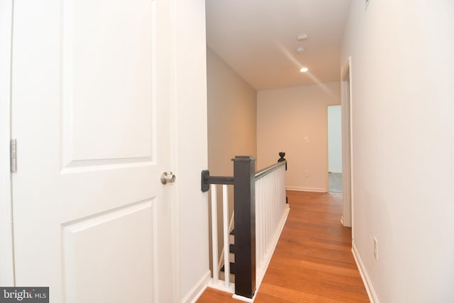 hall with an upstairs landing, recessed lighting, light wood-type flooring, and baseboards