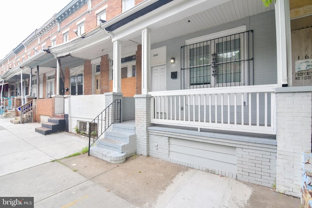 property entrance with covered porch and brick siding