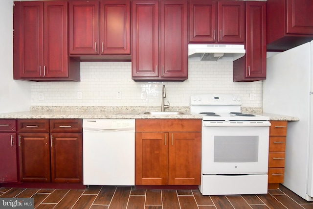 kitchen with white appliances, wood finish floors, a sink, dark brown cabinets, and under cabinet range hood