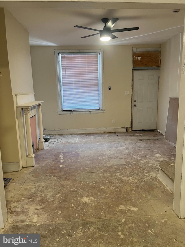 unfurnished living room featuring baseboards and a ceiling fan