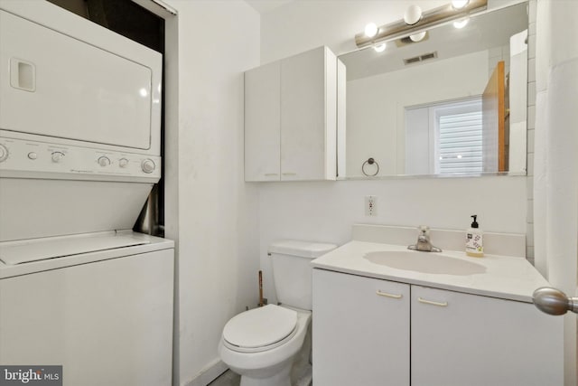 bathroom featuring toilet, stacked washer / dryer, vanity, and visible vents