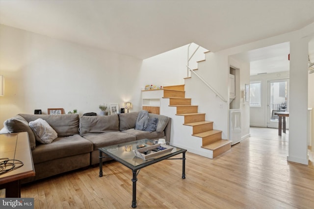 living room featuring stairway, light wood-style flooring, and baseboards