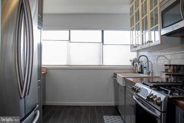 kitchen with a healthy amount of sunlight, baseboards, appliances with stainless steel finishes, and decorative backsplash