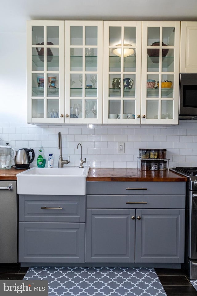 bar featuring appliances with stainless steel finishes, backsplash, and a sink