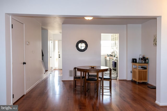 dining room featuring dark wood-style flooring, visible vents, and baseboards