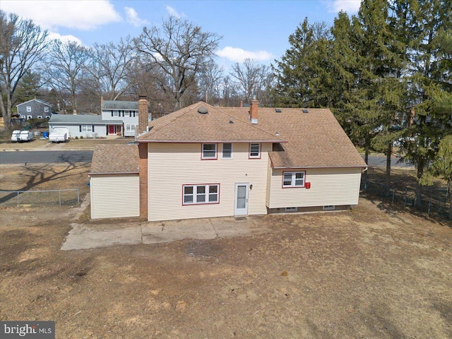 back of property with fence, a chimney, and a shingled roof