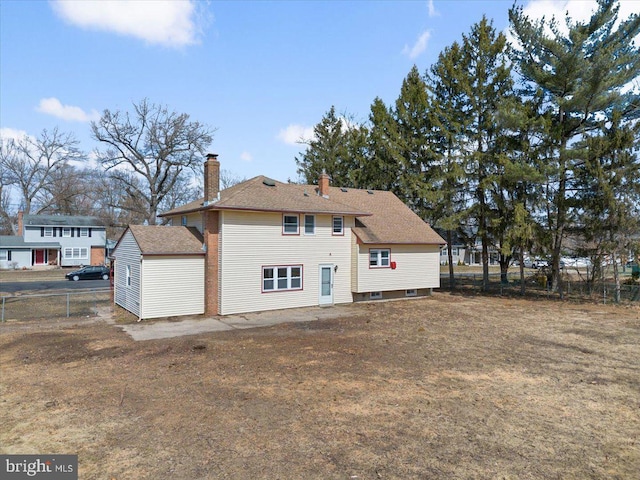 back of house featuring a chimney and fence