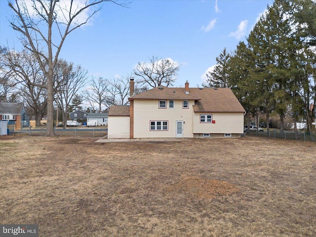 rear view of property featuring a chimney and fence