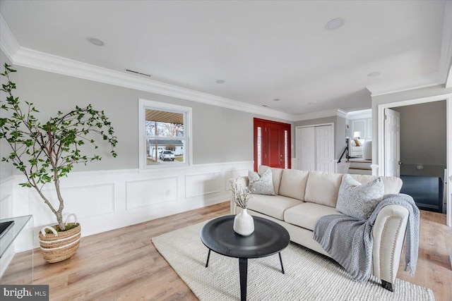 living room with wood finished floors, visible vents, stairs, wainscoting, and crown molding