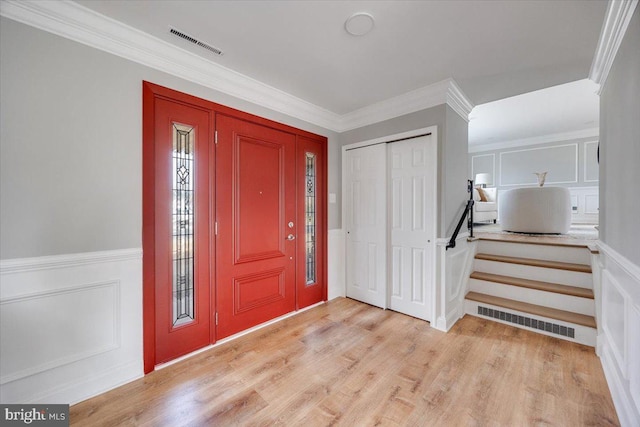 foyer with light wood-type flooring, visible vents, and a decorative wall