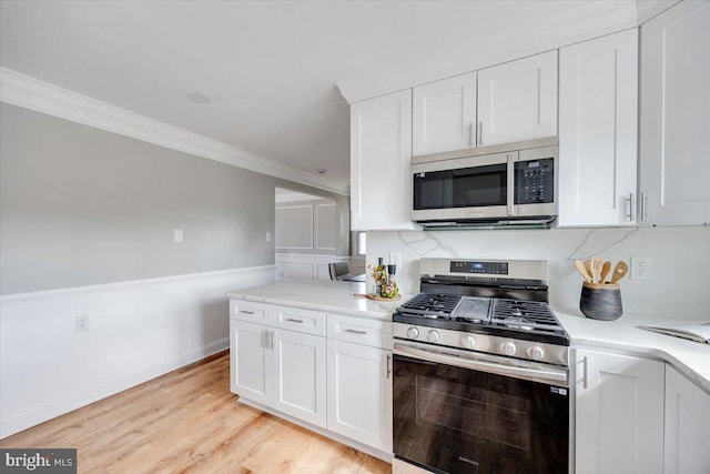 kitchen featuring baseboards, stainless steel appliances, white cabinets, crown molding, and light wood-type flooring