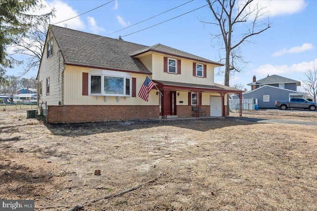 view of front facade featuring a garage, brick siding, roof with shingles, and fence