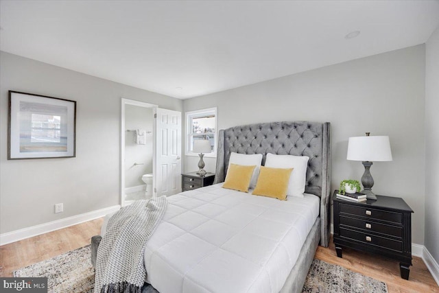 bedroom with ensuite bathroom, baseboards, and wood finished floors