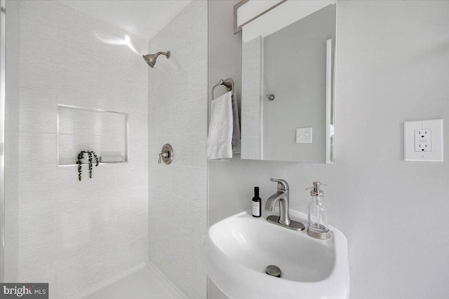 bathroom featuring a tile shower and a sink