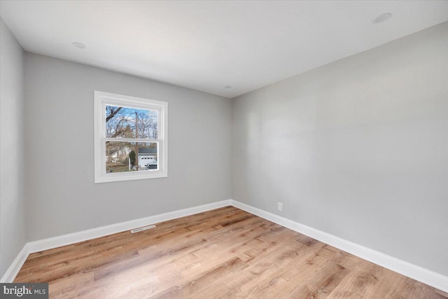 spare room with visible vents, baseboards, and wood finished floors