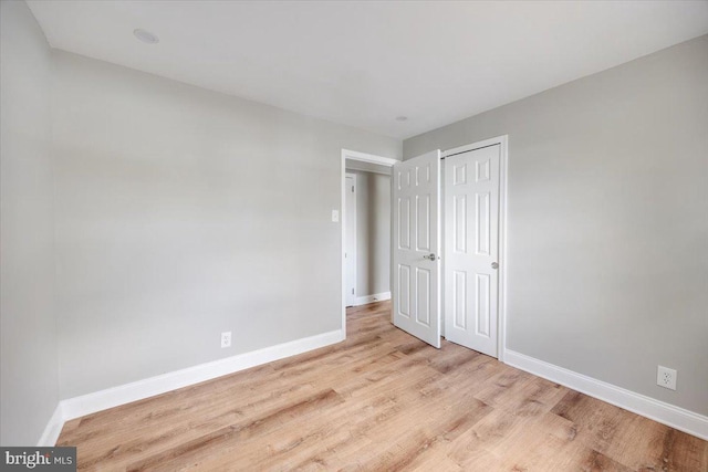 unfurnished bedroom with light wood-style floors, baseboards, and a closet