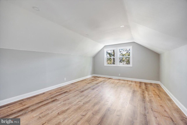 additional living space with baseboards, wood finished floors, and vaulted ceiling