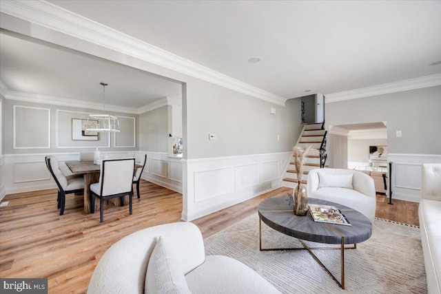 living room with light wood-style flooring, stairs, and a decorative wall