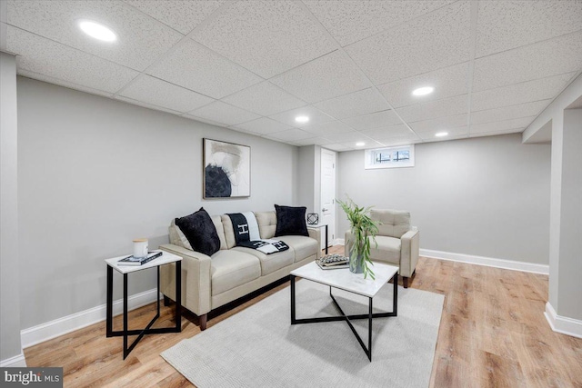 living area featuring recessed lighting, baseboards, light wood-type flooring, and a paneled ceiling