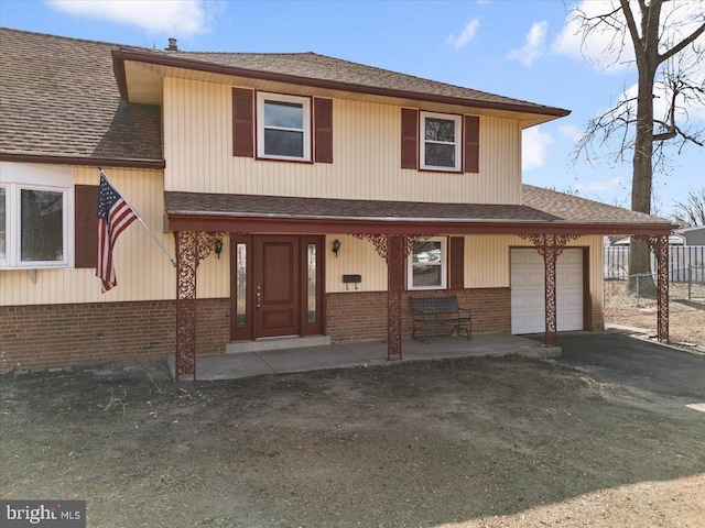 view of front of property featuring driveway, roof with shingles, a porch, an attached garage, and brick siding