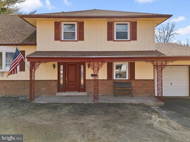 view of front of home featuring a garage, covered porch, brick siding, and roof with shingles