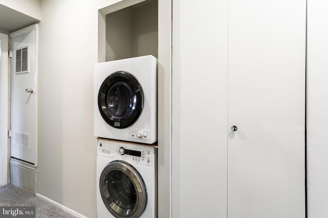 laundry area featuring baseboards, visible vents, carpet floors, stacked washing maching and dryer, and laundry area