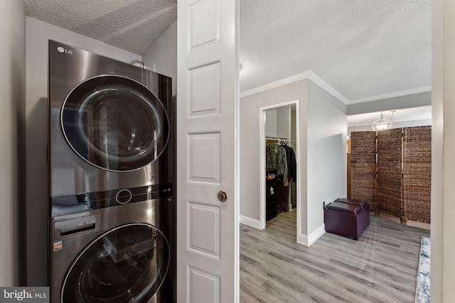 laundry room featuring wood finished floors, baseboards, laundry area, stacked washer / drying machine, and a textured ceiling